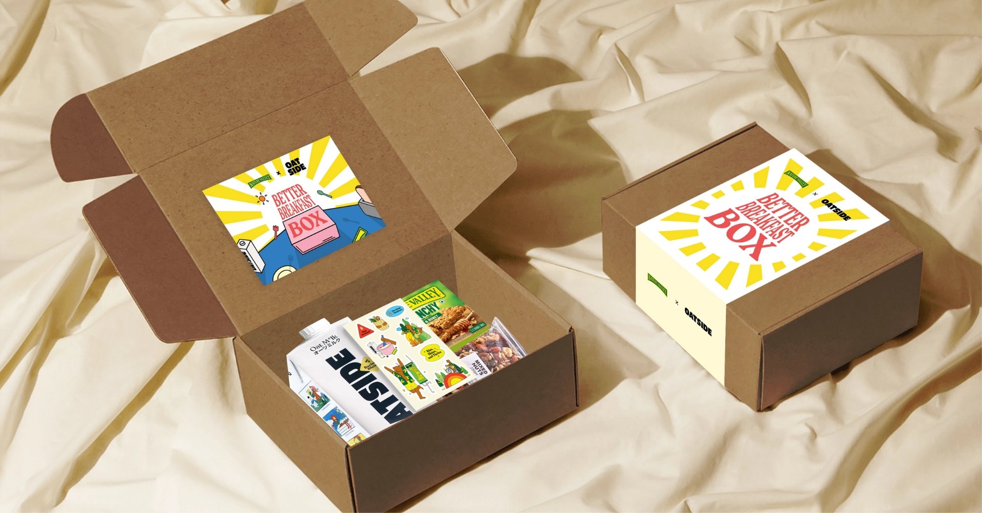 Two open brown cardboard boxes with 'Better Breakfast Box' branding display an assortment of breakfast items, including Nature Valley bars and a milk carton, designed by a creative digital marketing agency in Malaysia.