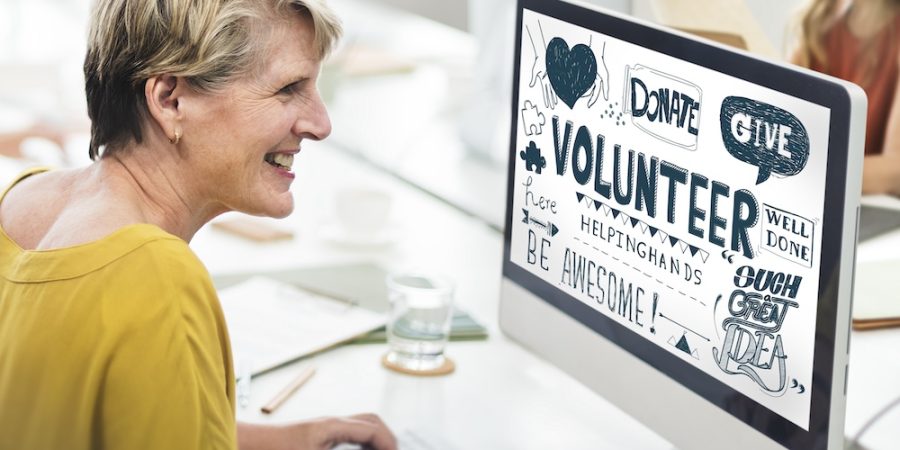 A lady working on a computer device that displays "volunteer", "donate" etc highlighting about non profits